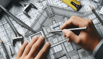 A scale ruler and measurement tools being used on a construction drawing.
